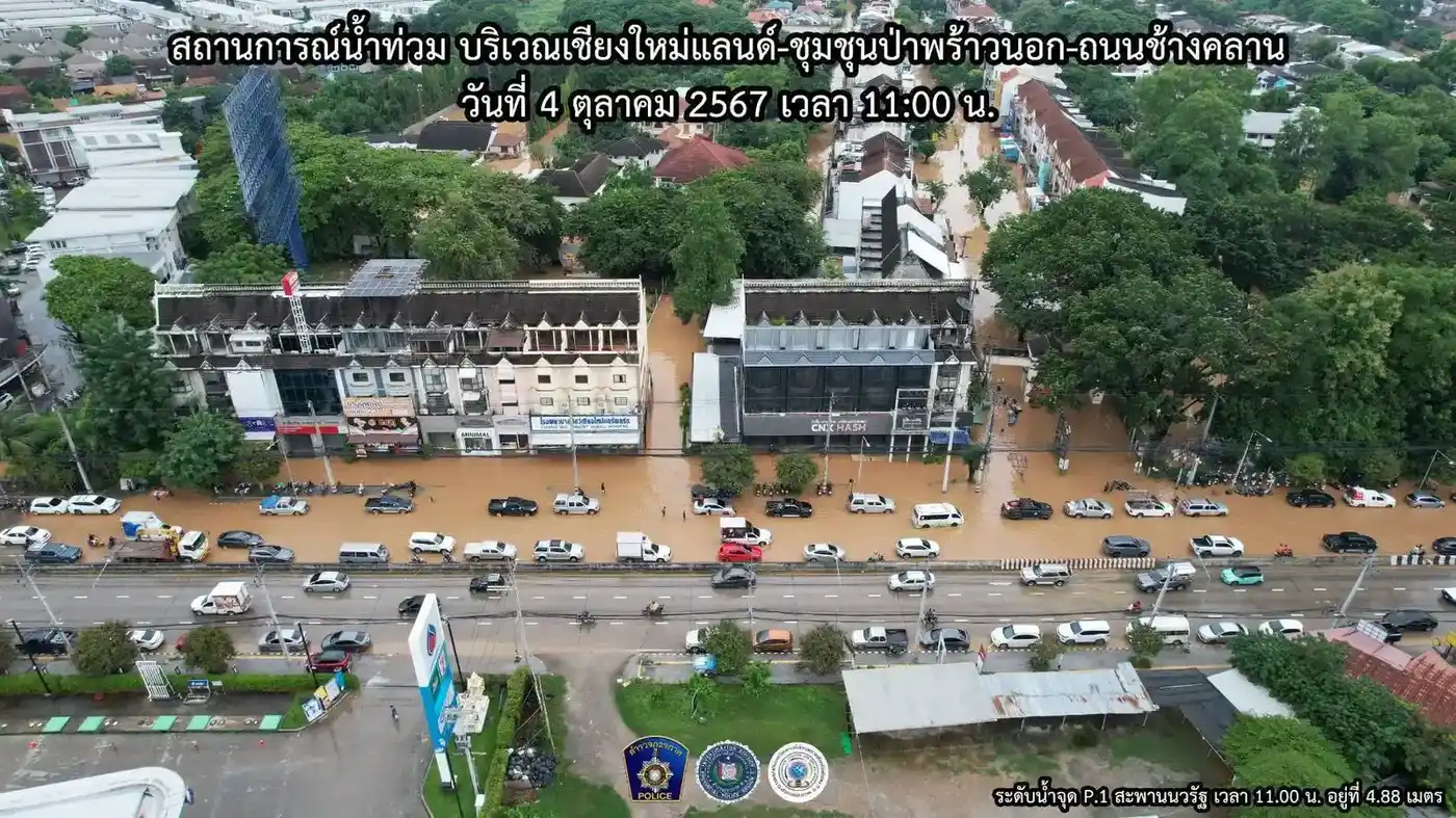 Flooded street near Chiang Mai Land with vehicles pushing through brown floodwater