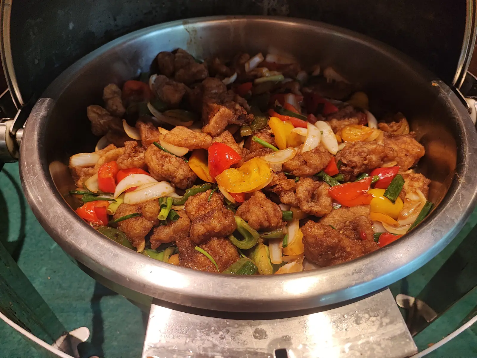 Crispy fried chicken with peppers and onions at the buffet